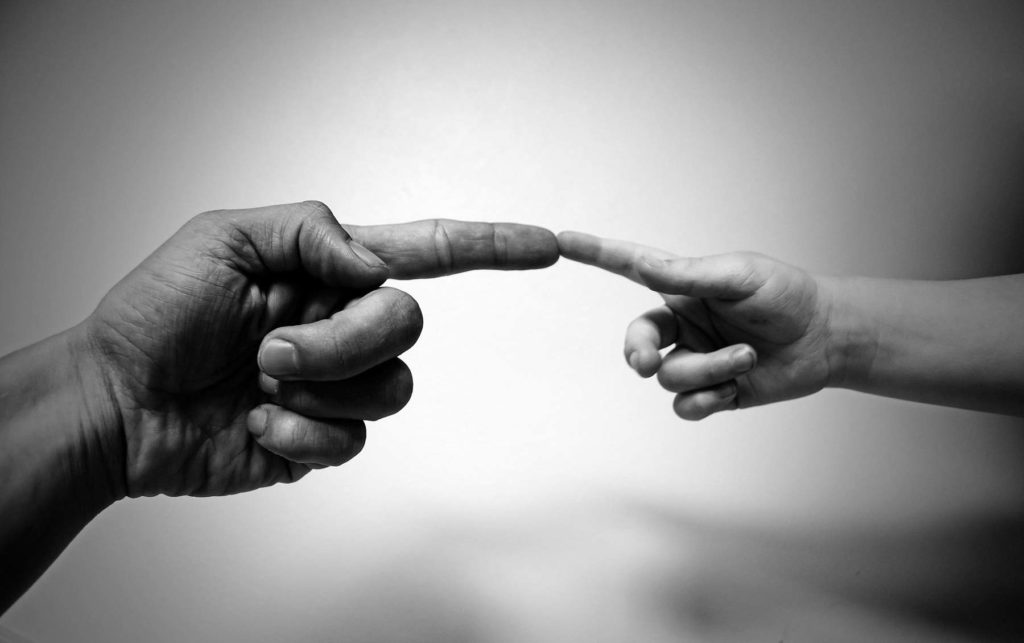 Photo de deux mains se rejoignant à la manière de Michelangelo